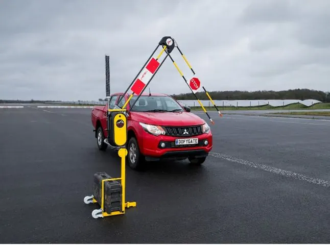 Pickup truck passing beneath the folded arm of an automatic traffic barrier